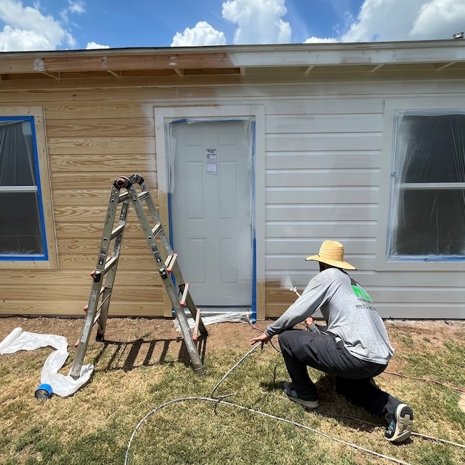 A painter is working on the outside of a home.