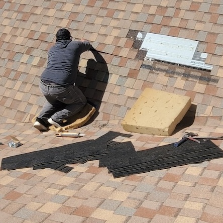 A roofer is working diligently on a roof repair.